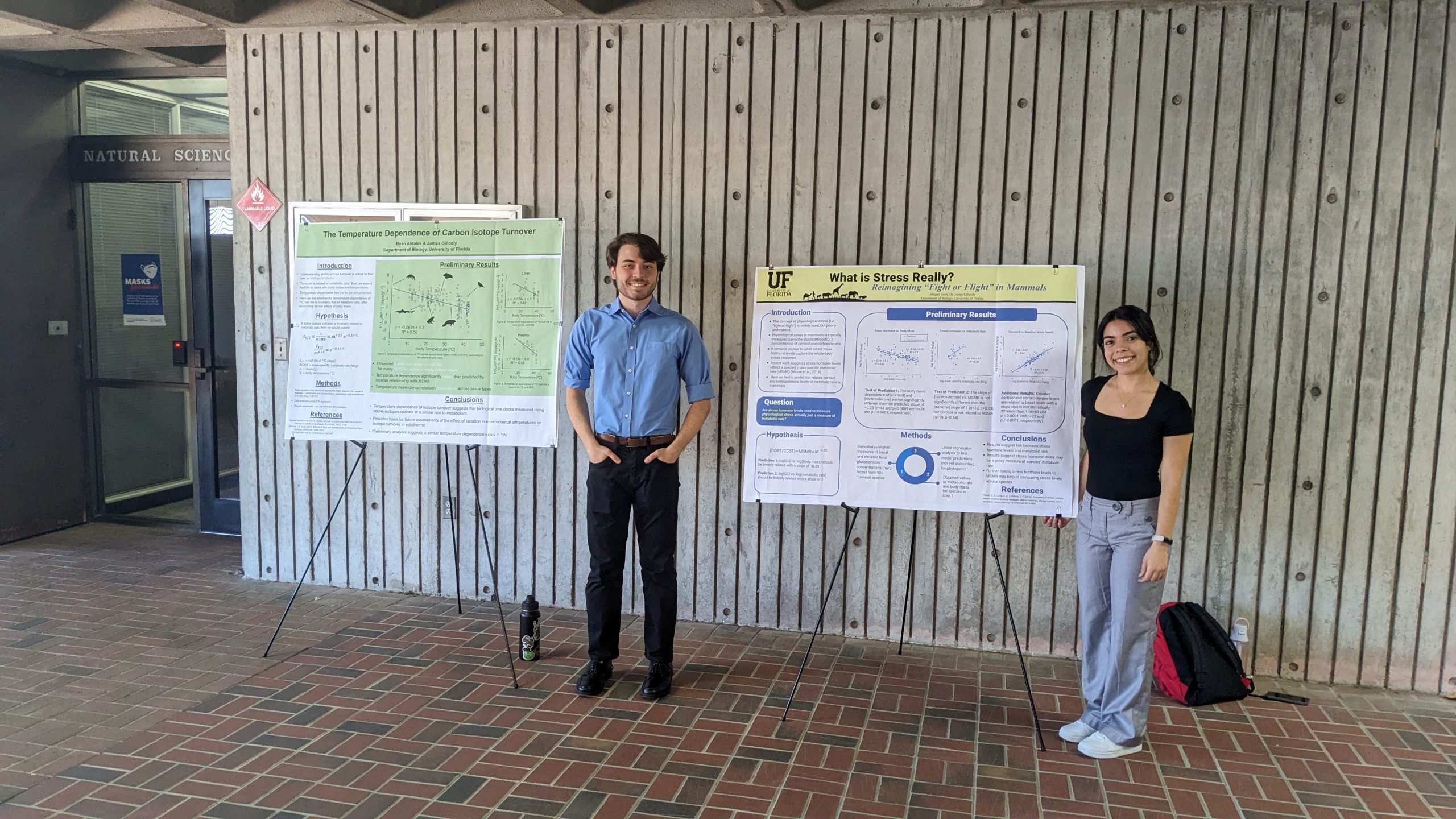 To the left: a student in a formal button-down shirt standing next to a green and white scientific poster with the title "The Temperature Dependence of Carbon Isotope Turnover."To the right: A student in a black blouse and formal pants standing next to a white and yellow scientific poster with the title "What is Stress Really?"