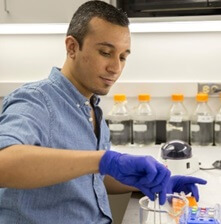 A lab worker wearing blue gloves.